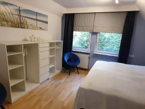 a bedroom with a bed and a blue chair at Holiday home in the fairytale forest in Hambühren
