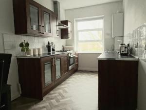 a large kitchen with wooden cabinets and a window at Earthling 1, Apartment in Blackpool
