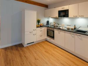 cocina con armarios blancos y suelo de madera en Frünn Stuuv Modern retreat en Ratzeburg