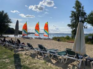 a group of sailboats on a beach with chairs and umbrellas at The Golfer's Blue in Unter Göhren