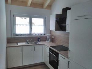 eine Küche mit weißen Schränken, einer Spüle und einem Kühlschrank in der Unterkunft Holiday home Baier in Philippsreut