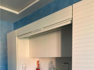 a kitchen with white cabinets and a blue wall at Royal Suite Sarzana in Sarzana