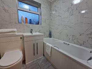 a bathroom with a tub and a toilet and a sink at Modern And Spacious 3 Bedroom Family House with Workspace in Colchester