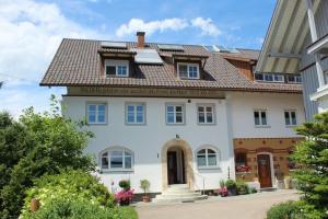 une grande maison blanche avec un toit marron dans l'établissement Apartment in Hergensweiler, à Hergensweiler