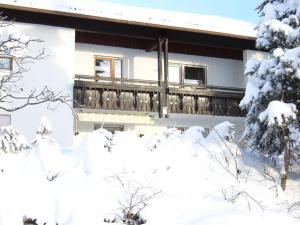 a house covered in snow with a balcony at Haus Nett Modern retreat in Stiefenhofen