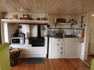 uma pequena cozinha com armários brancos e um fogão em Torpet em Sollebrunn