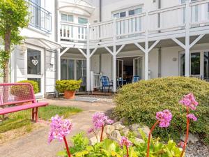 een wit huis met een roze bank en bloemen bij 2 Am Stadtwald Modern retreat in Kühlungsborn