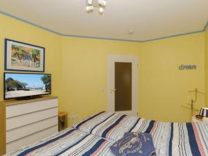 een slaapkamer met een bed en een dressoir met een televisie bij 2 Am Stadtwald Modern retreat in Kühlungsborn