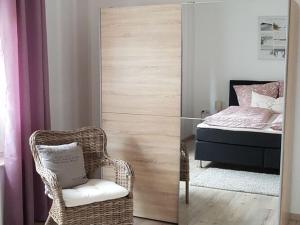 een slaapkamer met een bed en een rieten stoel en een spiegel bij Lovely apartment in Hesse in Hitzerode