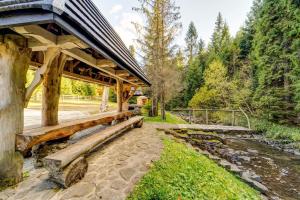 a wooden pavilion with a bridge over a river at Bacówka Polanki in Obidowa