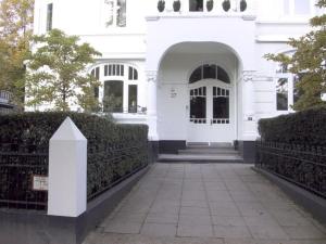 ein weißes Haus mit einem Tor und einem Gehweg in der Unterkunft Hamburg-Stad-Alsterparel in Hamburg