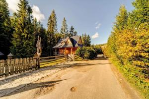 ein Haus auf einer unbefestigten Straße neben einem Zaun in der Unterkunft Bacówka Polanki in Obidowa