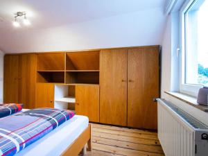 um quarto com uma cama, armários de madeira e uma janela em Holiday apartment Alstaden 1 em Oberhausen