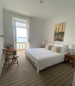 a white bedroom with a large bed and a window at Hotel Glavovic in Lopud Island