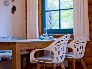 2 chaises blanches assises à côté d'une table et d'une fenêtre dans l'établissement Mitterdorf Modern retreat, à Mitterfirmiansreut