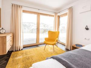 ein Schlafzimmer mit einem gelben Stuhl vor einem Fenster in der Unterkunft Holiday apartment in Seis am Schlern in Seis am Schlern