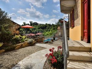 - une terrasse avec une table, un parasol et des fleurs dans l'établissement Freisa at Villa Pesce, à Mombaruzzo