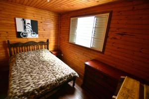 a bedroom with a bed in a log cabin at Hostel Cuesta in Botucatu