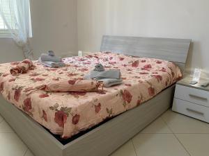 1 Schlafzimmer mit einem Bett mit rosa geblümter Bettdecke in der Unterkunft Appartamento Casa vacanza fronte mare in Venetico
