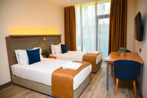 a hotel room with two beds and a desk at New Wave Apart-Hotel in Batumi