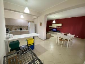 eine Küche mit einem weißen Tisch und einer roten Wand in der Unterkunft Appartamento Casa vacanza fronte mare in Venetico