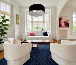 een woonkamer met een witte bank en 2 stoelen bij La Feuilleraie - Maison de charme avec piscine in Compiègne