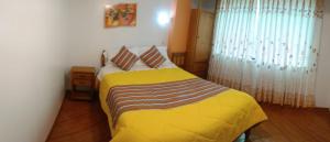 ein Schlafzimmer mit einem Bett mit gelber Bettwäsche und einem Fenster in der Unterkunft Lhotse Hostel B&B in Huaraz