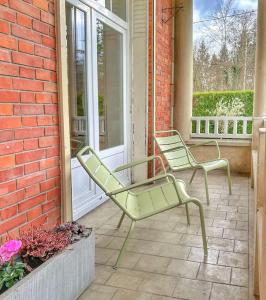 twee groene stoelen op een veranda bij La Feuilleraie - Maison de charme avec piscine in Compiègne