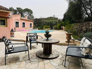 um pátio com uma mesa e cadeiras e uma piscina em Villa Conception em Le Thoronet