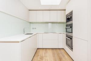 a white kitchen with white cabinets and a wooden floor at Boutique Covent Garden Apartment in London