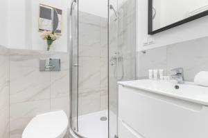 a white bathroom with a shower and a sink at Cosy Studios near the Old Town in Gdańsk by Renters in Gdańsk