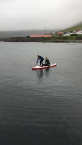 dos personas en una tabla de paddle en el agua en Seaside Cottage, en Oyndarfjørður