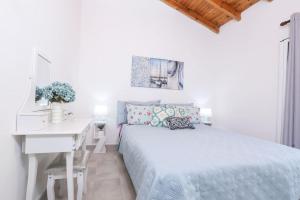 a white bedroom with a bed and a desk at Casa Niovi, Acharavi in Acharavi