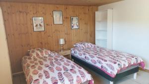 1 dormitorio con 2 camas y paredes de madera en La marmotte Appartement privatif 2 chambres proche du lac d'aiguebelette en Saint-Béron