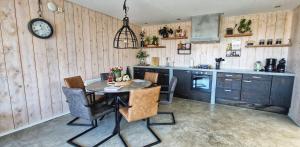 a kitchen with a table and chairs and a clock at Vakantiehuis De Bunker in Julianadorp