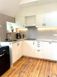 uma cozinha com armários brancos e piso em madeira em Appartement Sneek em Sneek