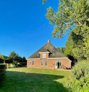 uma grande casa de tijolos vermelhos num campo de relva em Appartement Sneek em Sneek