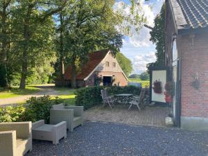 un patio con mesa y sillas frente a un edificio en Erve Het Roolvink Boerderij Appartementen 40-50 M2 en Enschede