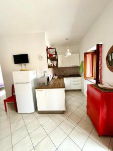 a kitchen with a white refrigerator and a red chair at Trilocale climatizzato con cortile in San Teodoro