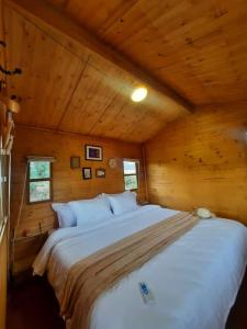 1 cama blanca grande en una habitación de madera en El Glamping de Calixto, Villa de Leyva, en Sáchica