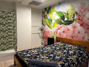 een slaapkamer met een bed met een bloemschilderij aan de muur bij Sky World Cozy Home in Auckland