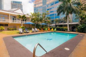 a swimming pool with chairs and a building at Waikiki Heritage Hotel in Honolulu