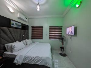 1 dormitorio con 1 cama blanca y ventilador en Racvity Homes Limited, en Akwa