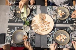 a group of people sitting around a table with pizza at zum Sausaler - Boutique Hotel-Pension Südsteiermark in Sankt Nikolai im Sausal