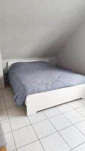 ein weißes Bett auf einem Fliesenboden in einem Zimmer in der Unterkunft Appartement les argousiers in Oye-Plage