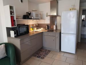 La cuisine est équipée d'un réfrigérateur blanc et d'un four micro-ondes. dans l'établissement Au Epicéah, logement à la campagne, à Valence