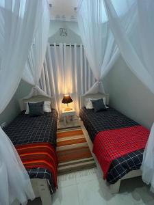 ナクルにあるPinnacle Alpine Houseの白いカーテンが備わる客室のベッド2台