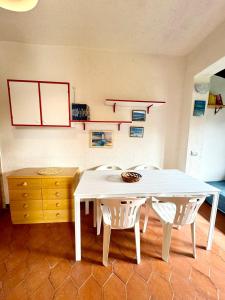 a white dining room table with two chairs and a dresser at Bilocale al Villaggio degli ulivi SAN TEODORO in San Teodoro