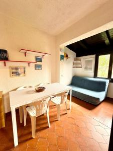 a dining room with a table and chairs and a couch at Bilocale al Villaggio degli ulivi SAN TEODORO in San Teodoro