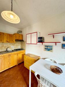a kitchen with wooden cabinets and a white table at Bilocale al Villaggio degli ulivi SAN TEODORO in San Teodoro +9 photos